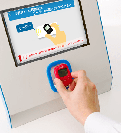 歩数計をリーダーにかざす写真